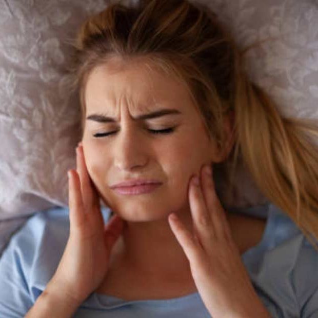 Girl holding her jaw in pain from TMJ